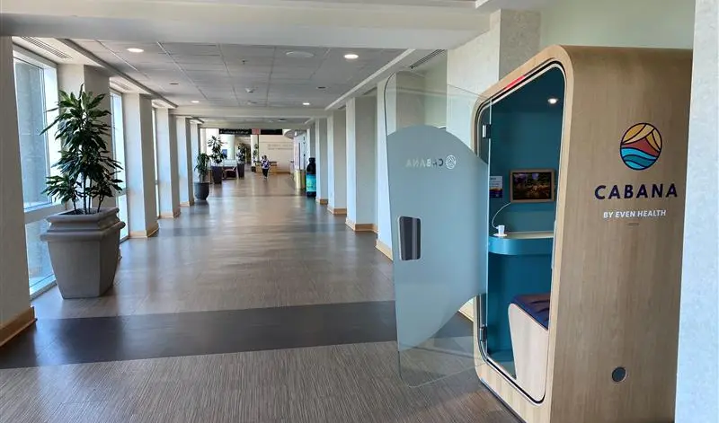 View down a long hallway in a hospital. A booth labeled Cabana Pod is on the right.